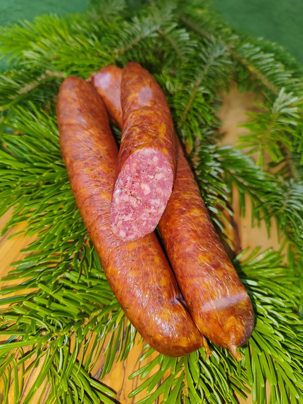 Wildräucherbratwurst kalt geräuchert im Ring, präsentiert auf Tannengrün